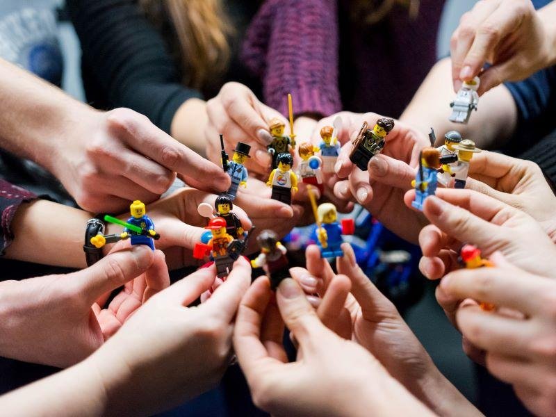 Manos en el medio sosteniendo muñecos de Lego pequeños.